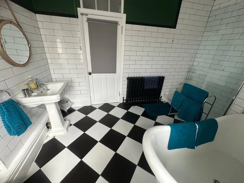 Bathroom with freestanding bath, white basin and black-and-white tiled floor.