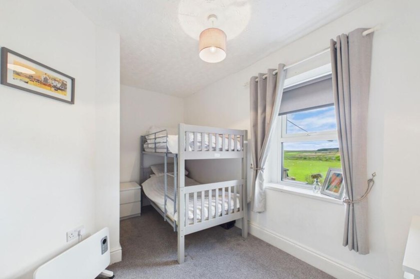 White bunk bed beside a window looking towards open countryside.